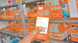 Un regente farmacéutico muestra un medicamento dentro de su establecimiento; al fondo, una variedad de fármacos para la venta. Foto: Nicolás Quinteros.