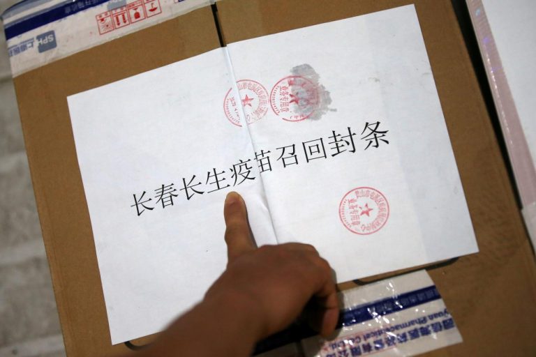 Staff from a local disease prevention and control centre points to a paper notice for recall on a sealed package of vials containing the rabies vaccines manufactured by the vaccine maker Changsheng Biotechnology in Huangshan