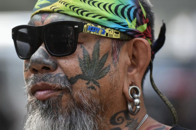 A Thai activist with a marijuana tattoo on his face gathers with others during a campaign for the legalisation of medical marijuana near Government House in Bangkok