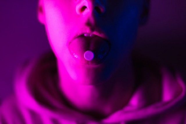 Joven con una pastilla de LSD en su lengua.