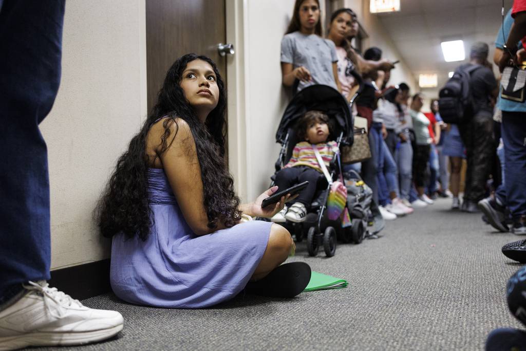 Yolexi Cubillan, de 19 años, sentada en el suelo mientras espera en la fila con otros migrantes en una oficina del Departamento de Servicios Humanos de Illinois el lunes 28 de agosto de 2023 en Chicago.