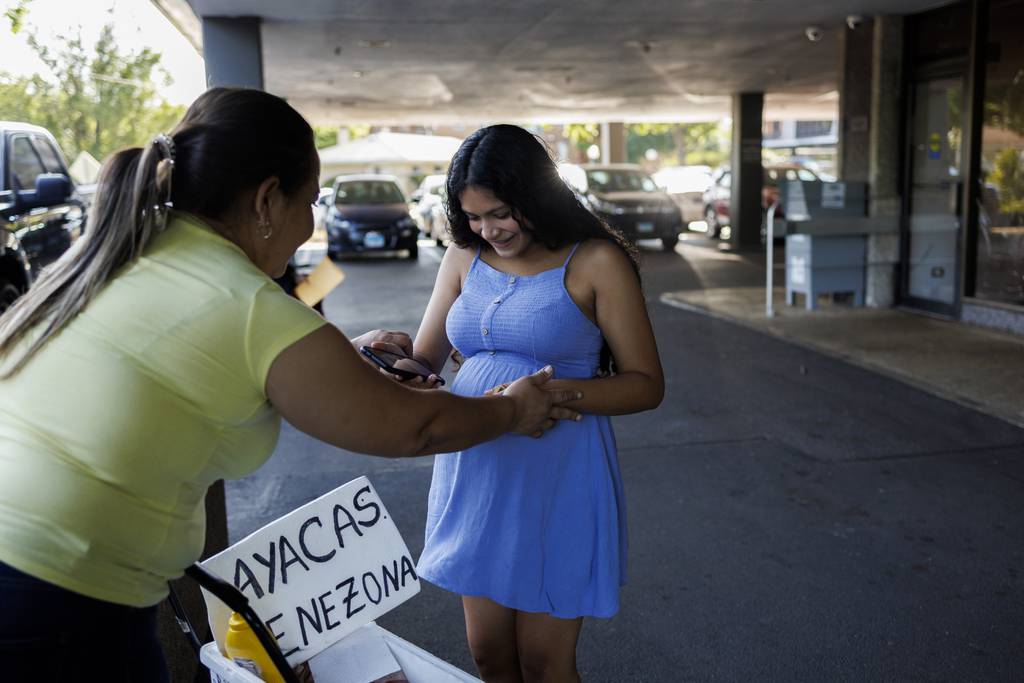 Yolexi Cubillan, de 19 años, compra comida mientras espera su cita en una oficina del Departamento de Servicios Humanos de Illinois el lunes 28 de agosto de 2023 en Chicago.