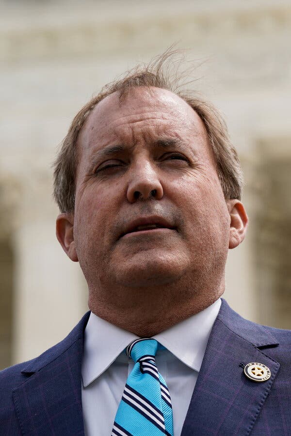 Ken Paxton lleva un traje azul y una corbata azul a rayas y habla con los periodistas ante la fachada de la Corte Suprema de Estados Unidos.